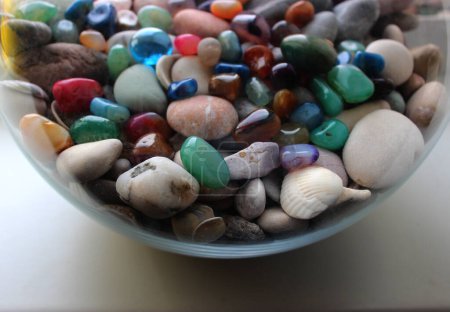 Round glass jar full of colorful quartz gemstones and sea pebbles