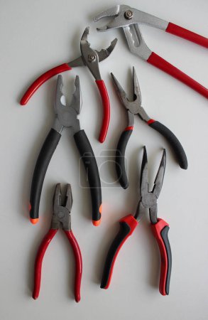 Photo for Slip Joint Pliers, Groove Pliers, Needle Nose Pliers And Linesman Pliers Laid Out On White - Royalty Free Image