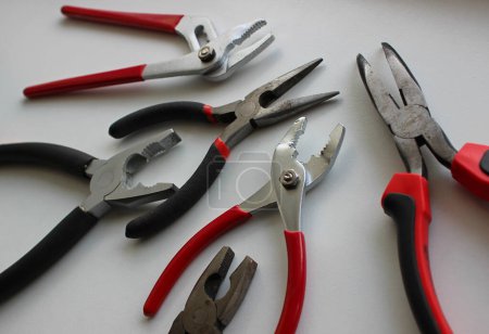 Photo for Variety types of pliers with rubberized handles laid out on a white surface - Royalty Free Image