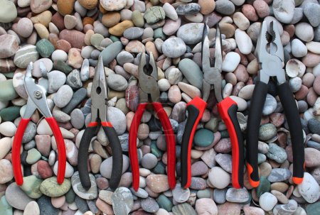 Photo for Slip Joint Pliers, Groove Pliers, Needle Nose Pliers And Linesman Pliers Laid Out Arranged On Size On A Stones Background - Royalty Free Image