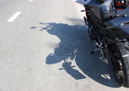 Photo for The shadow of a motorcycle standing on the side of the highway on a sunny day - Royalty Free Image