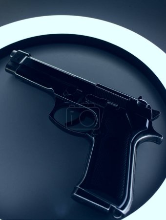 Photo for Contour Of Black Metal Pistol Gun On White Surface With Blue Backlight - Royalty Free Image