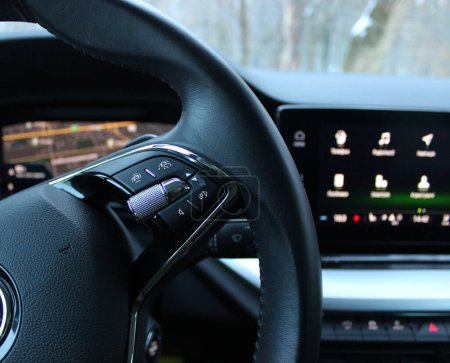 Geschwindigkeitsbegrenzer-Modus und Kollisionsvermeidungssystem Tasten auf einem Lenkrad mit verschwommenem Monitor mit Menüsymbolen in modernen Auto 