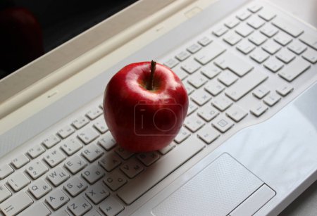 Téléchargez les photos : Pomme rouge fraîche sur clavier d'ordinateur portable avec caractères latins et cyrilliques - en image libre de droit