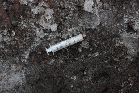 Foto de Concepto de drogadicción callejera. Jeringa médica usada en suciedad congelada con escombros de hielo - Imagen libre de derechos