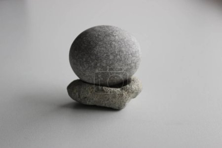 Photo for Perfect oval granite stone balances on stone stand isolated on white - Royalty Free Image
