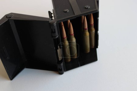 Standard 5.45 ammo in ammo storage box on white surface 