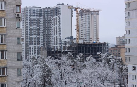 Construction of a multi-apartment high-rise residential complex near a green park at winter conditions