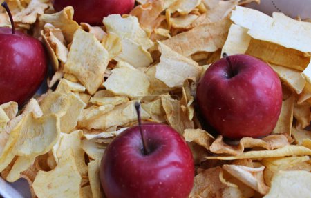 Frische Äpfel im Karton, gefüllt mit getrockneten Apfelscheiben. Heimische Apple Chips Kochkonzept Foto