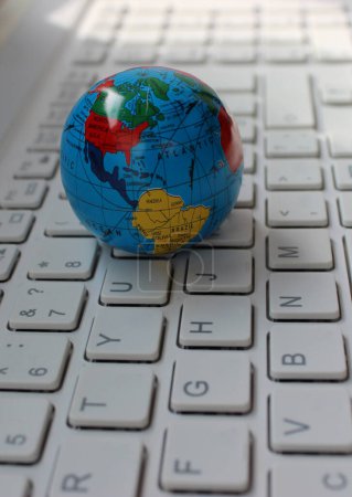 Nahaufnahme des Globus mit kartierten Nord- und Südamerika-Kontinenten, die auf Computertasten liegen 