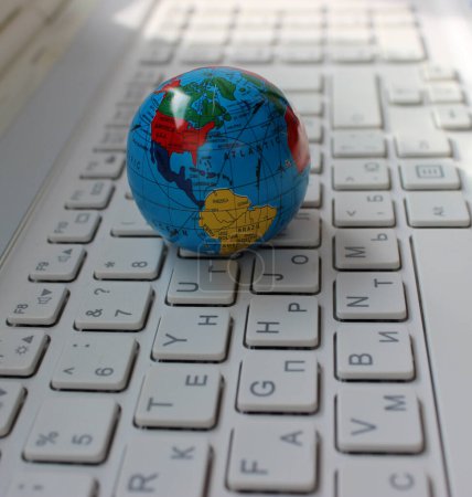 Nahaufnahme des nord- und südamerikanischen Kontinents auf einem Globus auf einer zweisprachigen Desktop-Tastatur 