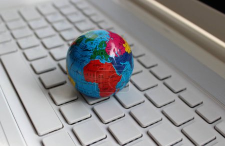 Nahaufnahme des Globus-Modells, das auf einer sauberen leeren Computertastatur liegt. Global Solutions Konzept Archivbild 