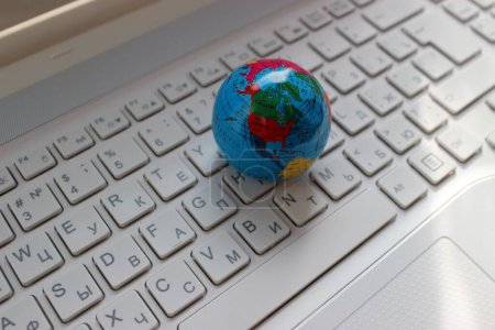 Nord- und Südamerika-Kontinente auf einem Globus-Modell auf einer Laptop-Tastatur mit lateinischen und kyrillischen Buchstaben kartiert 