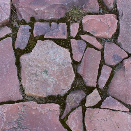 Red granite stones placed in an old masonry texture background. Square stone background stock photo
