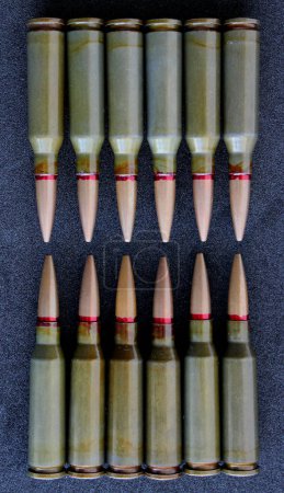 Top view of twelve bullets in two groups lined up head to head on clean black fabric. Stock Photo For Vertical Bullets Backgrounds 