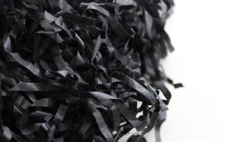 Verflochtene Streifen zerknüllten schwarzen Packpapiers isoliert auf weiß. Papierspäne für Dekoration Archivfoto