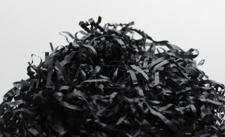 Mischstapel aus schwarzem Papier, in Streifen auf weißem Hintergrund geschnitten. Papier Müllkonzept Archivfoto