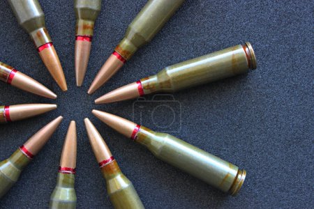 Top view of bullets in the form of flower on clean black fabric. Stock Photo For Military Backgrounds
