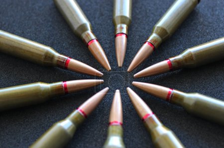 Circle of live ammunition on black silk velvet surface angle view