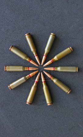 Combat bullets laid out in a circle shape on a black surface vertical stock photo