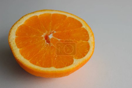 Orange mûr coupé en deux sur une surface blanche sur le côté de l'image. Photo de stock pour milieux de fruits 