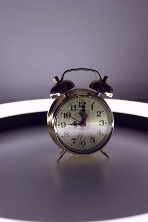 Photo de stock verticale de réveil Bell Clock sur table de nuit éclairée 