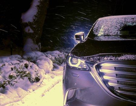 A car is parked in the driveway of a private house, waiting for snowfall and safe driving conditions. Snow driving and risk on the road stock photo 