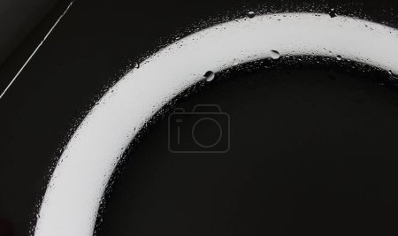 Téléchargez les photos : L'eau tombe sur un verre sur le fond incurvé de texture légère néon - en image libre de droit