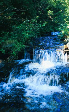 Blaues Wasser in kleinem Wasserfall im Gebirgsbach 