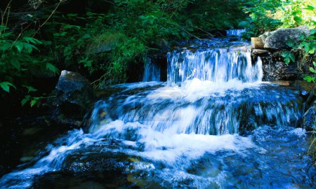 Kristallklares Wasser fließt die Kaskaden eines kleinen Flusses im Wald hinunter
