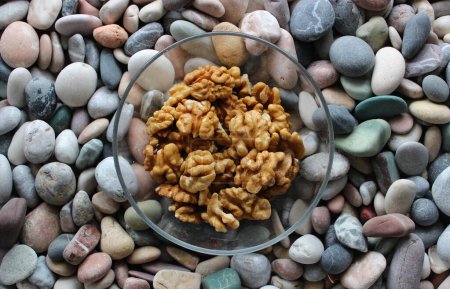 Peeled Walnuts In Glass Bowl On Colored Pebbles Surface