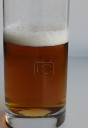 Beer glass without handle half filled with craft brown ale closeup view