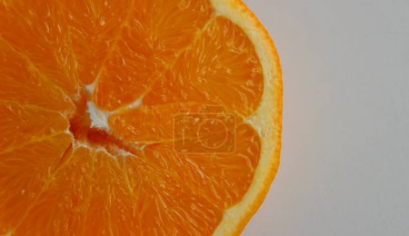 Saftige Orangenscheibe auf einer weißen Fläche an der Seite des Bildes. Archivfoto für Zitrusfrüchte Hintergründe 