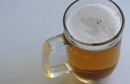 Rich color of indian pale ale in a classic beer glass on white surface top view