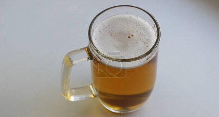 Verre à bière énorme avec poignée classique remplie de bière brune artisanale recouverte de mousse isolée sur blanc