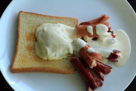 Hotelfrühstück Archivfoto. Verschiedene Grillwürste und Frankfurter serviert mit französischem Ei auf einem heißen Toast 