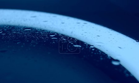 Eau saupoudrée sur verre propre dans la lumière bleue Macro Shot Stock Photo 