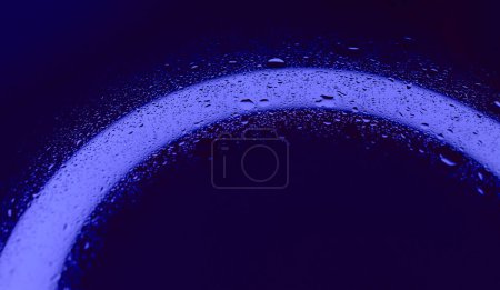 Tröpfchenmuster auf nassem Glas mit intensiver blauer Hintergrundbeleuchtung