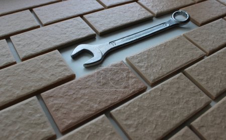 Combination Wrench Inside Decorative Brickwork Closeup Angle View. Stock Photo For House Repairing Illustration