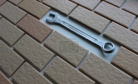 Shiny chrome wrench in place of a missing tile on a fully tiled surface