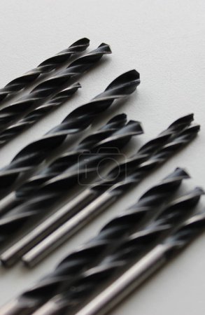 Black Drill Bits For Metal On Clean White Plastic Sheet WIth Selective Focus  