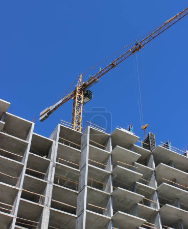 Tower Crane Lifts Concrete Blocks To The Upper Floors Of A High Rise Building Under Construction