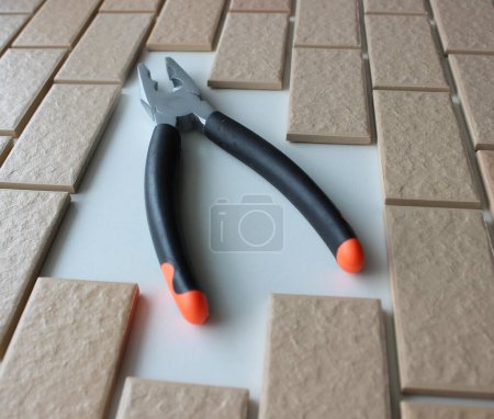 Rubberized Handles Of Pliers On Free Space On A Surface Covered With Brick Tiles. Home Repairing Square Stock Photo 
