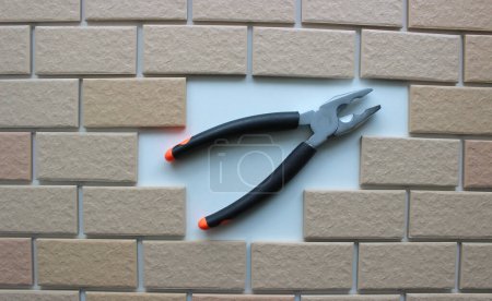 Opened jaws pliers on clean place of a missing tiles on a fully tiled surface