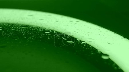 Textur von Spritzwasser auf grün beleuchteter Glasoberfläche. Chroma Key Droplet Textur Hintergrund