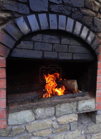 Feuer brennt in einem verrußten Ziegelholzofen Details 