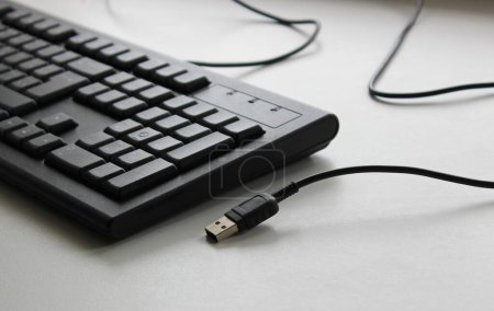 USB-Stecker der kabelgebundenen Computertastatur auf weißer Oberfläche. Plug And Play PC-Teile Illustratives Archivfoto 