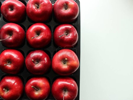 Téléchargez les photos : Plateau en plastique avec pommes rouges fraîches sur la surface blanche à côté de l'image - en image libre de droit