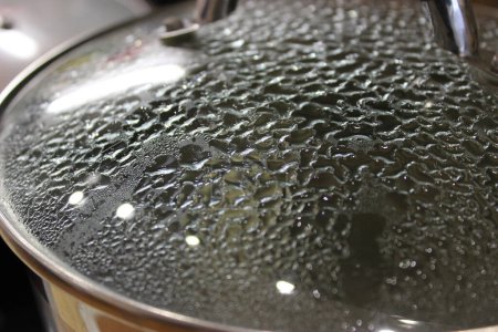 Gotas de condensación caliente en la tapa de vidrio de una sartén  