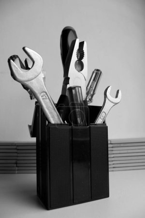 Bunch of carpentry tools in black plastic cup. Monochrome stock photo for workshop illustration 